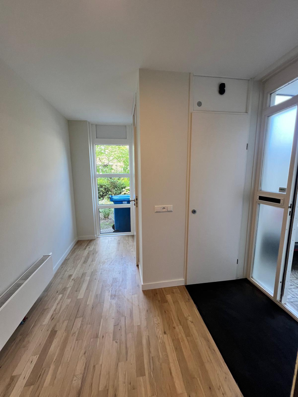 Hal met lichte wanden en zicht op de tuin in Nootdorp