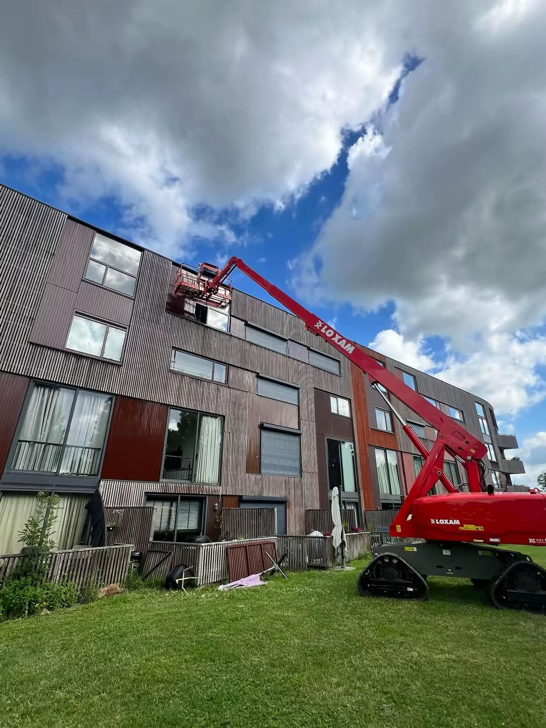 Schilderwerk op hoogte met een hoogwerker langs de gevel van een bouwproject