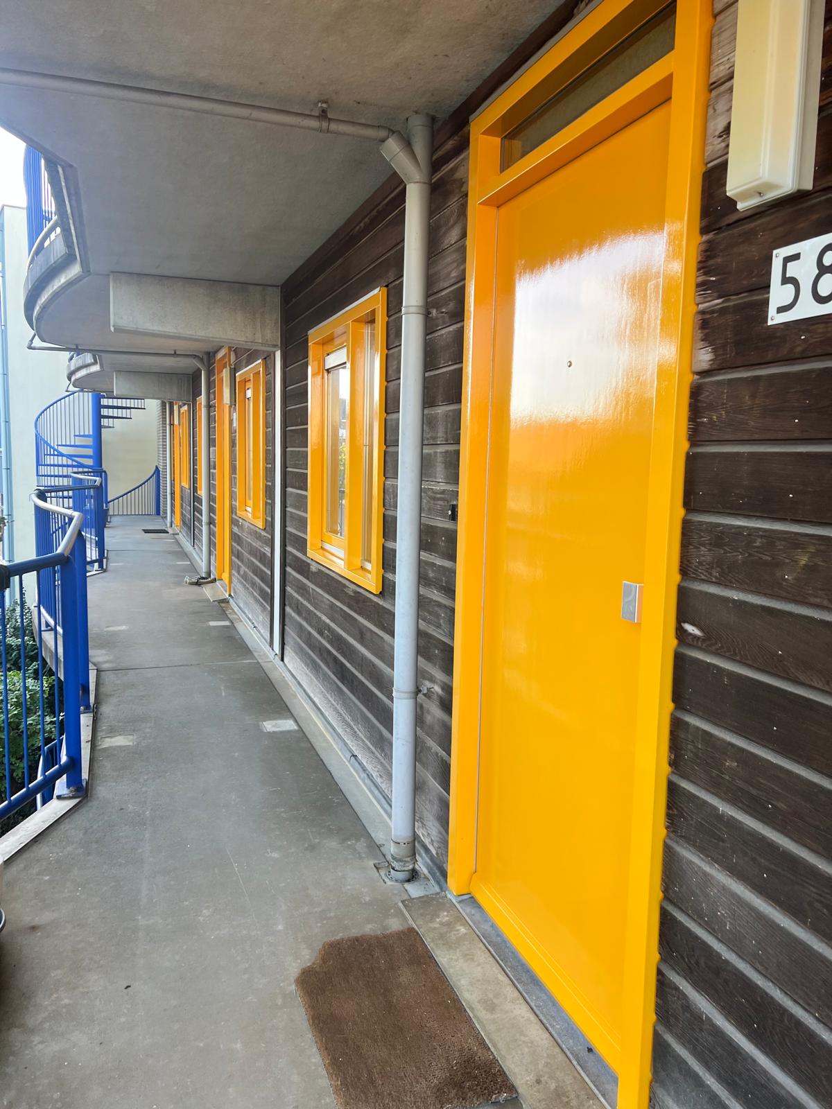 Galerij van een appartementencomplex met geschilderde kozijnen en deuren